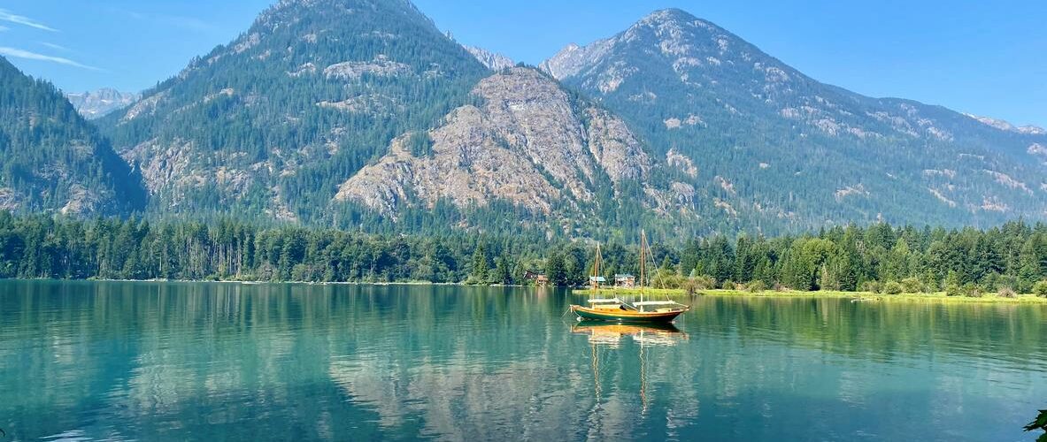 A waterfront view of Lake Chelan in Washington State on a summer day with mountains in the background.