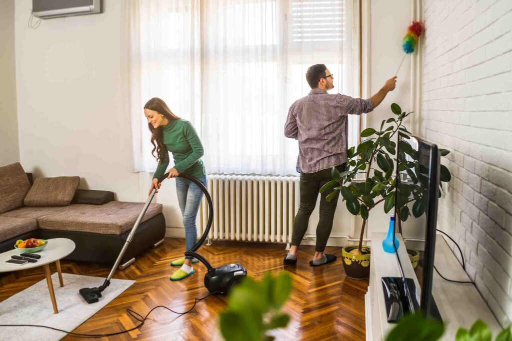 A man and woman vacuum and dust their home.